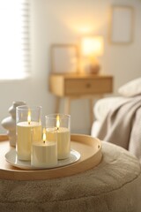 Beautiful LED candles and vase on pouf indoors, closeup. Space for text