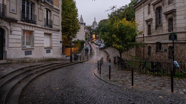 Day to night timelapse of a small street in the Montmartre district of Paris, France with Basilica of Sacre Cour in the background