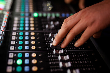 Hand adjusting audio mixer faders during event