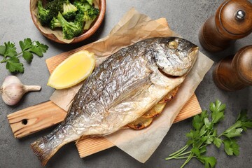 Tasty grilled fish, broccoli and spice on grey table, flat lay