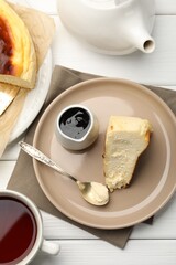 Delicious Basque cheesecake, chocolate sauce and tea on white wooden table, flat lay