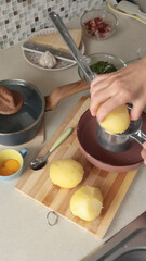 Anonymous user mash boiled potatoes in kitchen. Making mashed potatoes. High-quality farm products.