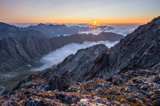 Aerial view of jagged peaks piercing through a sea of morning mist, as the sun casts a golden glow over Maly Ladovy stit, Tatranska Javorina, Presov Region, Slovakia.