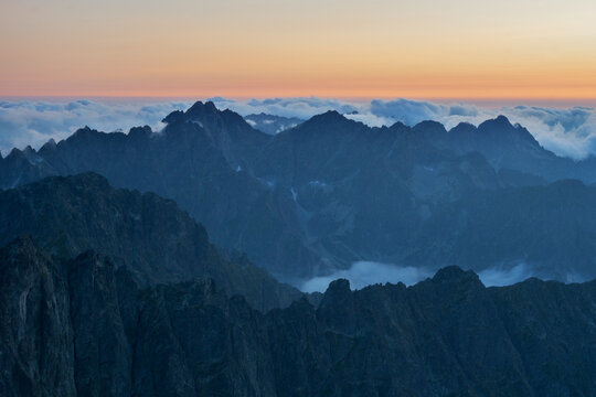Aerial view of sharp mountain peaks piercing through a sea of clouds under a soft, pastel sky in Maly Ladovy stit, Tatranska Javorina, Presov Region, Slovakia.