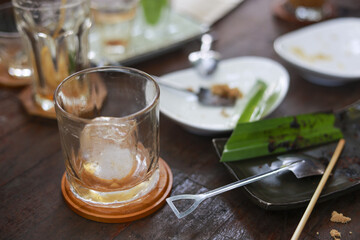 Empty glass on coaster and dirty plate with leftover food after finished meal. messy wooden table in cafe or restaurant reflecting sense of contentment