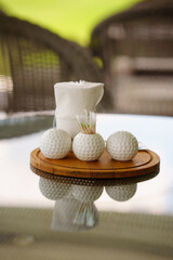 Golf accessories on a wooden tray at a sunny patio