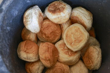 Top view of homemade fresh baked bread roll in dark bucket. comforting pile of rustic and traditional golden brown bake good, delicious and wholesome meal component