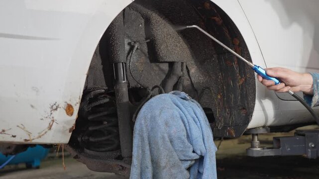 Closeup of DIY lanolin oil rust protection applied with nozzle in garage showing eco friendly corrosion prevention