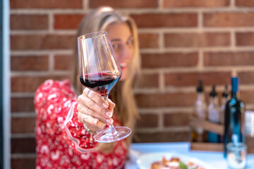 Beautiful blonde woman smiling with red wine glass focus on elegance fine wine moment and stylish celebration vibe