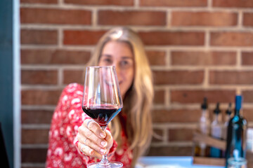 Smiling blonde lady with red wine glass focus on elegant details luxury lifestyle mood of celebration and happiness