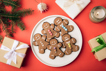 Gingerbread cookies with colorful candies and christmas gifts on red background. Christmas flat lay. Top view