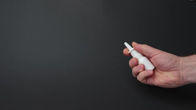 Hand holding a white nasal spray bottle, showcasing the grip and motion, as the camera smoothly zooms in to highlight the product's details and functionality