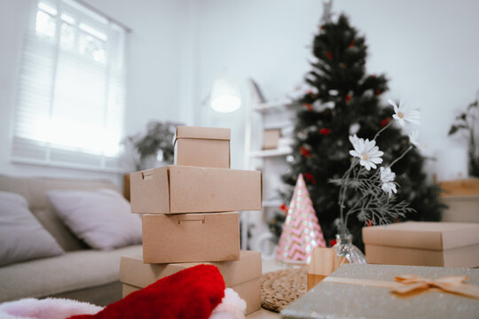 Young woman wearing a Santa hat decorating a Christmas tree with red berries and pine cones, smiling happily in a cozy home.