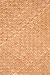 A full-frame close-up showcases the tight, herringbone or chevron pattern of a natural light brown woven mat or basket texture