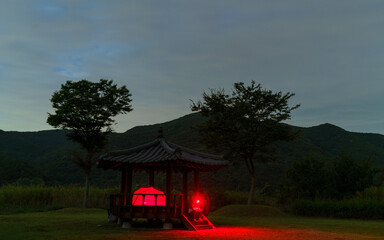 Red light glows from a tent in a gazebo