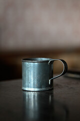 Still life of an empty old vintage tin cup on a wooden table