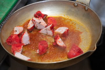Chicken Tikka Masala Preparation Cubes of tandoori chicken simmering in a rich tomato-based curry sauce inside a traditional metal pan, capturing the vibrant colors, steam and authentic cooking