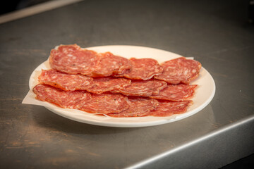 Italian Salami Slices Thinly sliced cured salami arranged neatly on a white plate, showcasing marbled texture and rich red tones, perfect for charcuterie boards, antipasto platters gourmet appetiser