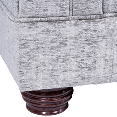 Detailed close-up of a grey chenille upholstered sofa base showing fabric texture and polished dark wood turned leg. Elegant craftsmanship for modern and classic interior design