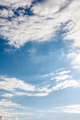 Obraz premium clear blue sky with white fluffy clouds. vertical nature background. soft cumulus cloudscape wallpaper on a bright day. fresh air due to reduced emission in summer atmosphere