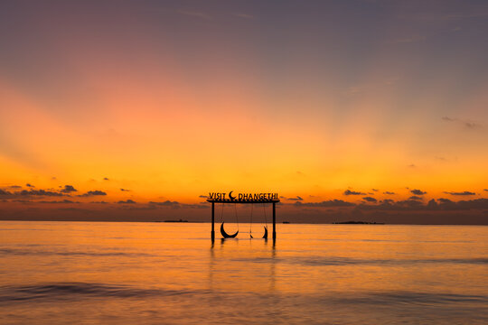 Sunset swing over calm ocean waters