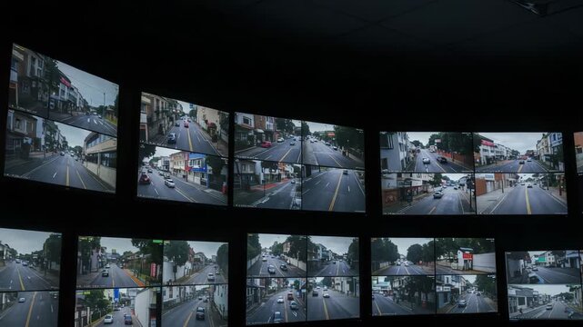 Monitors showing surveillance cameras in dark control room, security wall for traffic observation, multi-camera setup for building access, monitors used in night patrol, airport, mall, parking control