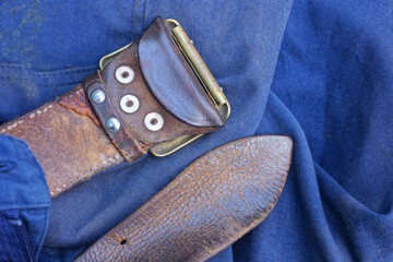 old brown leather belt with brass buckle on blue pants