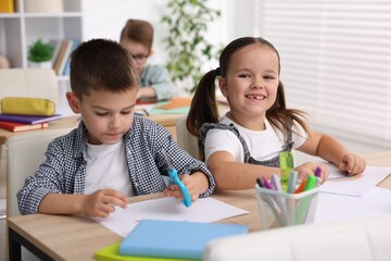 Cute children at wooden desks during art lesson in elementary school