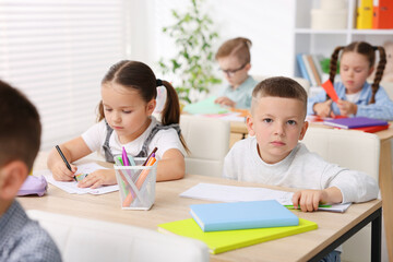 Fototapeta premium Cute children at wooden desks during art lesson in elementary school