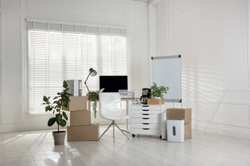 Moving day. Cardboard boxes, computer and furniture in office
