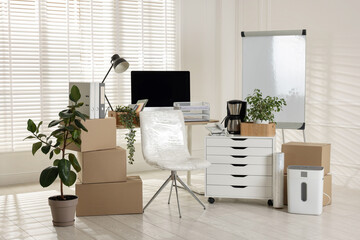 Moving day. Cardboard boxes, computer and furniture in office