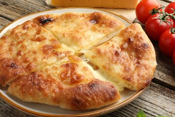 Delicious Megrelian khachapuri and products on wooden table, closeup