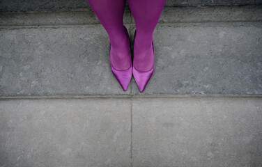Woman wearing purple tights and matching high heels standing on stairs
