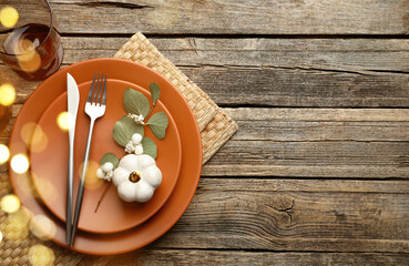 Autumn place setting, bokeh lights. Brown plates, cutlery and decor on wooden table, top view