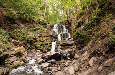 Shypit waterfall on the Pylypets River. Forest waterfall in Transcarpathia. Waterfall in rocky ravine with green trees around.