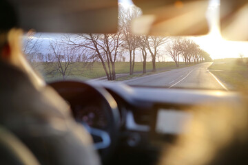 View of a road outside the city from a moving car through the windshield in the afternoon sun