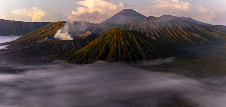 View of volcanic peaks rising majestically above a sea of ethereal mist under a pastel dawn sky, Bromo, East Java, Indonesia.