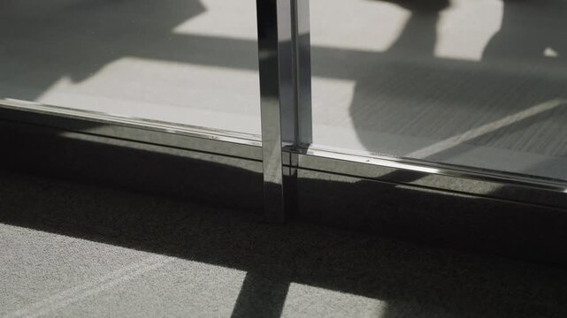 Shadows and silhouettes of people walking in line after boarding plane or disembarking entering airport terminal. Sunlight shining from glass windows in international airport as passengers pass by