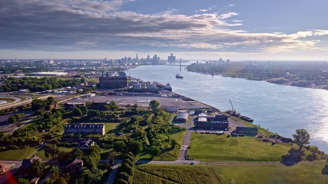 Camera drone passes over Gordie Howe Bridge, heading toward Detroit's industrial riverside.