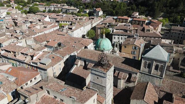 Drone flies over the rooftops of a charming Proven&ccedil;al town, surrounded by green hills and sunshine