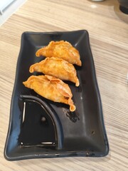 Fried dumplings with dipping sauce on a black plate