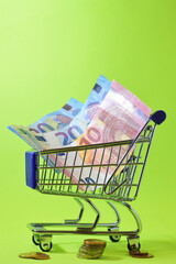 Euro coins and banknotes, green background, copy space. Vertical, close-up shot.