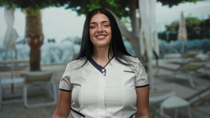 Woman smiling outdoors at a resort pool in a sunny, relaxing setting, highlighting vacation vibes...