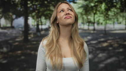Naklejka premium Woman covers ears with hands in park; pain frustration.