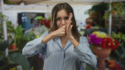 Woman wearing glasses and striped shirt making fighting gesture with fists among colorful flowers...