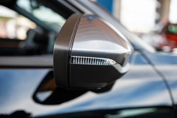 New car side view mirror with integrated turn signal light. Close up detail shot, shallow depth of...