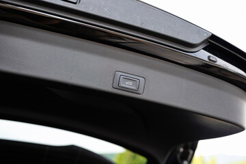 New car's electric or power close tailgate or boot lid button. Close up, wide angle view, no people