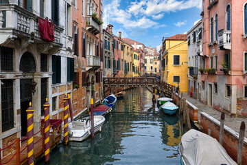 Narrow canal with bridge and boats in Venice, Italy. Architecture and landmark of Venice. Cozy cityscape of Venice.