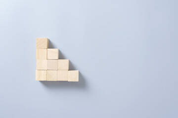 Wooden cubes stacked in ascending steps on gray background, symbolizing business growth, progress, success, teamwork, and goal achievement concept in minimal style.