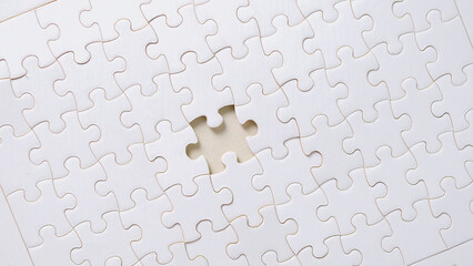 White puzzle with one missing piece on light background, symbolizing problem solving, teamwork, incomplete task, solution finding, and strategic thinking concept.
